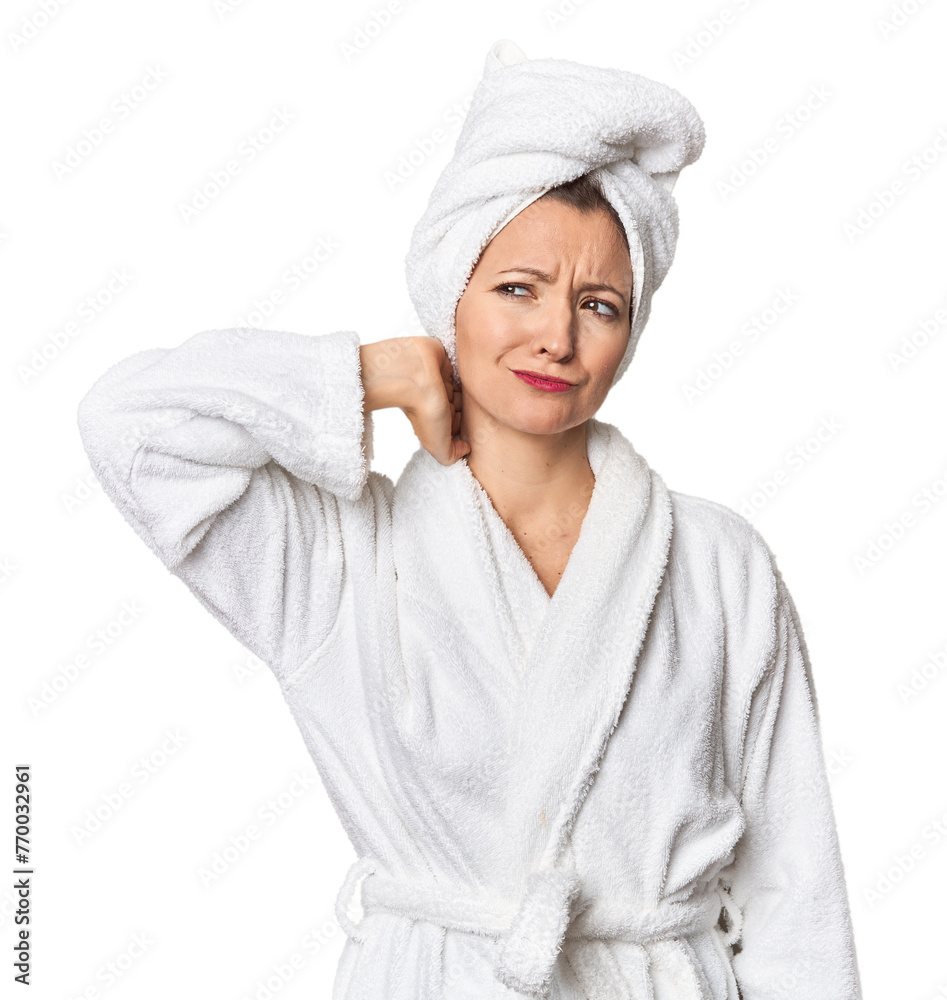 Caucasian woman in bathrobe and towel touching back of head, thinking and making a choice. Caucasian woman in bathrobe and towel touching back of head, thinking and making a choice.