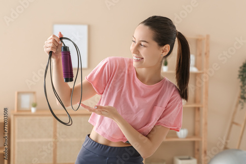 Sporty female blogger with skipping rope at home