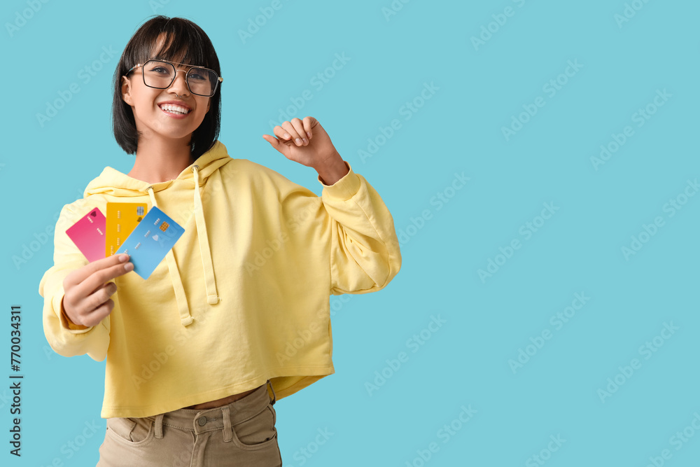 Beautiful young woman with credit cards on blue background Beautiful young woman with credit cards on blue background