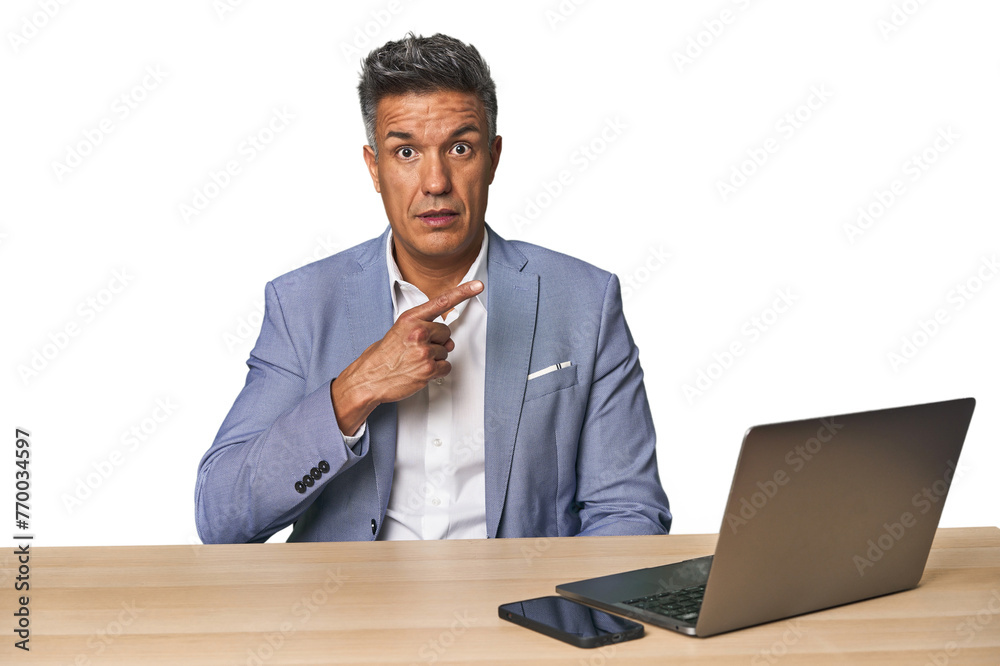 Elegant businessman at desk with laptop pointing to the side Elegant businessman at desk with laptop pointing to the side