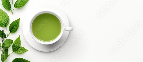 A refreshing cup of green tea served in a delicate teacup, with vibrant green leaves displayed on a saucer against a clean white background