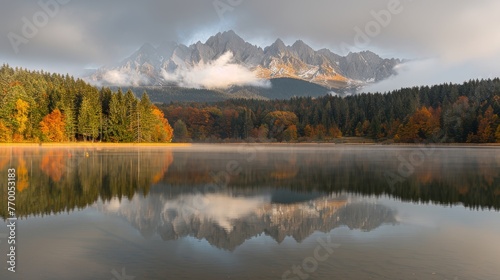  A serene lake enveloped by lush foliage, framed by majestic mountains and adorned with fluffy clouds above, with scattered trees in the foreground