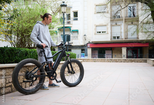 Young man in sports wear, renting and riding e-bikes in the city. Bike sharing city service