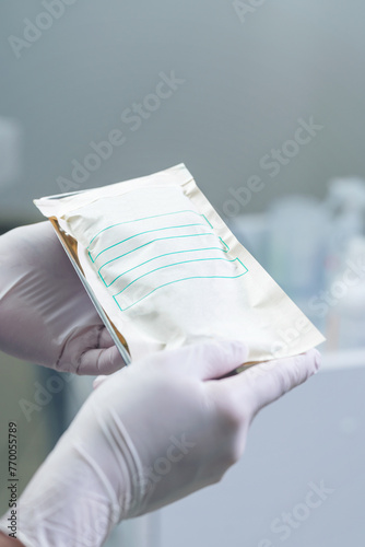 A girl in gloves holds a craft bag with sterile medical instruments for pedicure on a tray