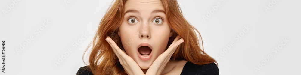 Charming woman with a shocked expression, hands raised to her face in surprise Charming woman with a shocked expression, hands raised to her face in surprise