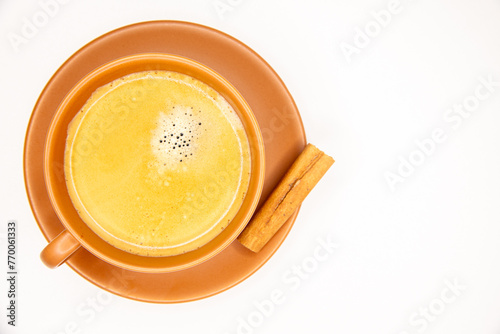 Xícara de café preto com espuma dourada, pires e xicara em terracota, bege, marrom, terra, rama de canela em fundo branco