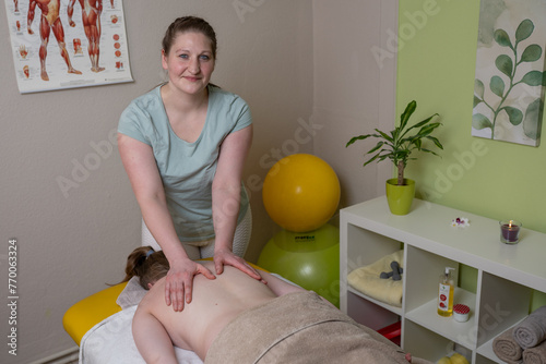 Physiotherapeutin massiert eine weibliche Patientin am Rücken