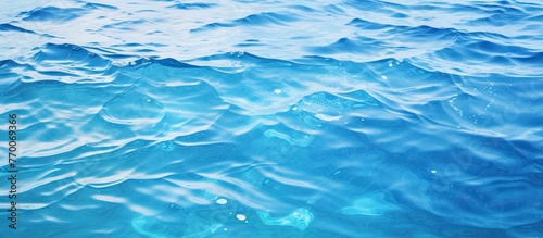A closeup shot of the electric blue water surface with wind waves creating a mesmerizing pattern. The fluid aqua solvent reflects the beauty of the ocean waves