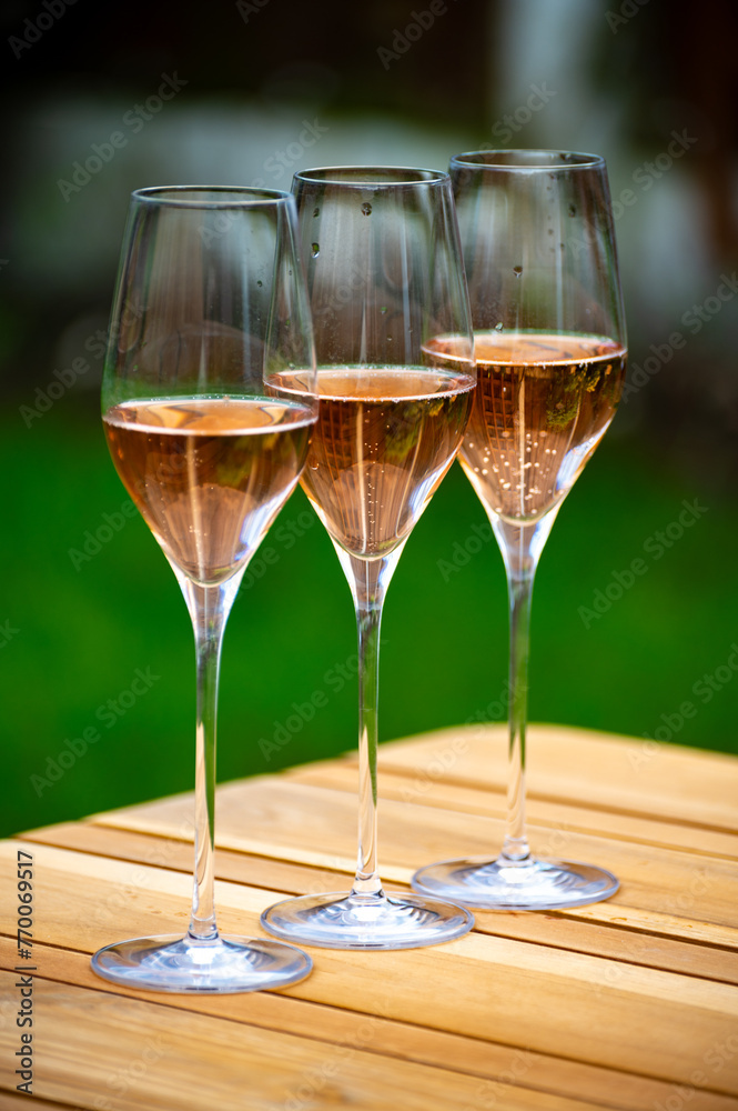 Naklejka premium Picnic on green grass with glasses of rose champagne sparkling wine or cava, cremant produced by traditional method in caves in Champagne region, France