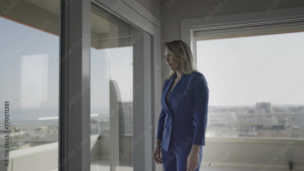 Serious and professional woman looks in the window at home Serious and professional woman looks in the window at home