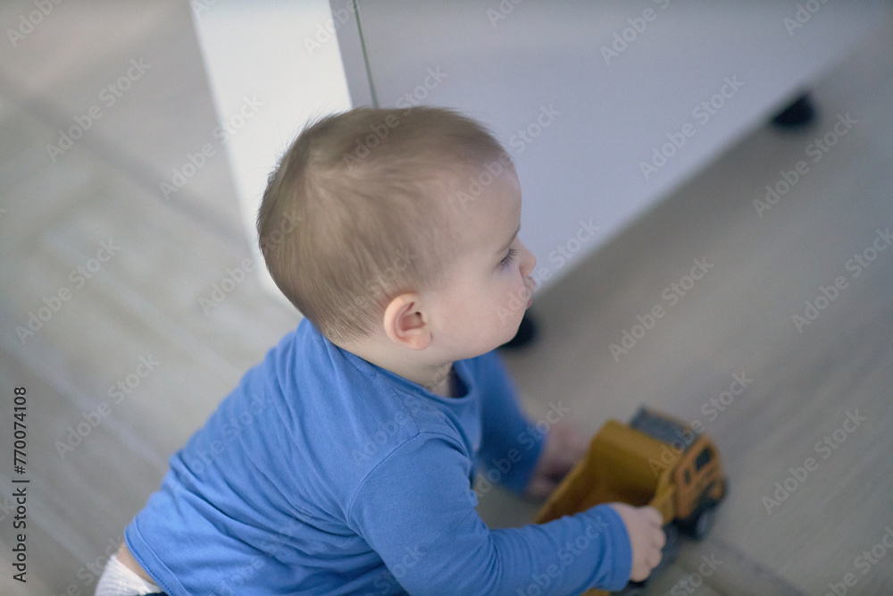 Fototapeta premium Baby Sitting on Floor Playing With Toy Truck