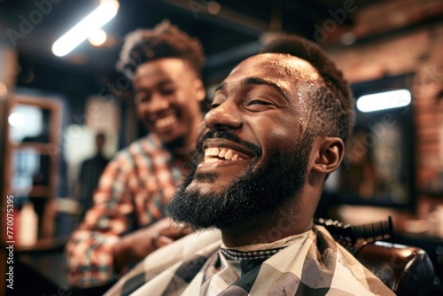 A smiling man with a beard and hair is sitting in the barber's chair