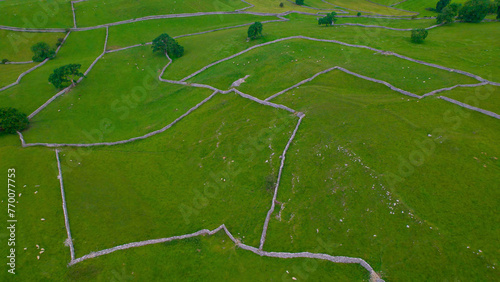AERIAL: Beautiful patchwork pattern of dry stone wall demarcating green pastures photo