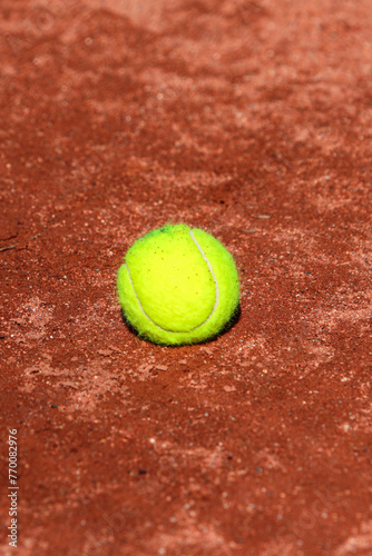 Detail of a tennis ball stopped on the ground of a clay tennis court during a sunny day