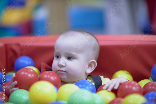 a one-year-old child, a boy, a joyful kid in toys, a lot of balls