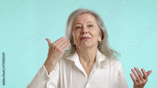 A delightful senior woman with eyes closed, hands gracefully raised as she savors the scent, indulging in the joyful experience of a pleasant fragrance on a light blue background. Camera 8K RAW.  photo