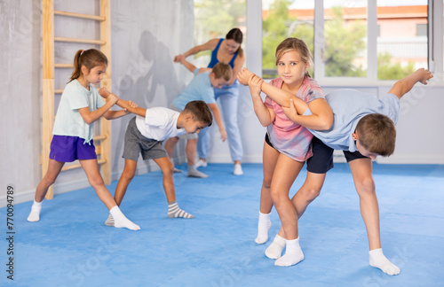 In training hall, children are working on arm twists, learning to control and subdue opponents.