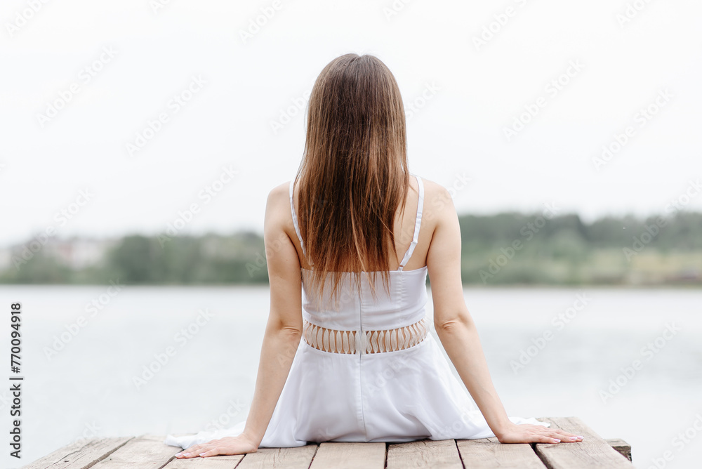 young woman sits at pier