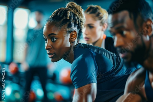 Three athletes are intensely focused as they perform exercises in a gym environment depicting determination and teamwork