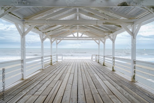 A serene white wooden pavilion overlooking the calm blue ocean on a cloudy day  offering a peaceful retreat