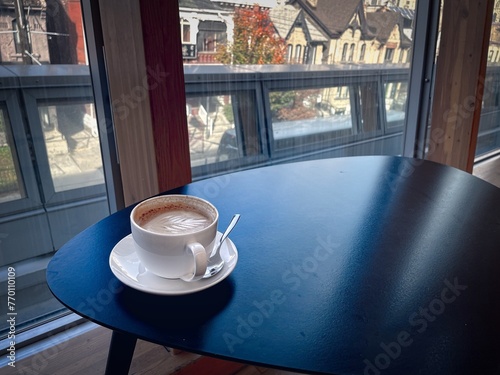 Photography enjoying a cup of latte on a saucer by the window
