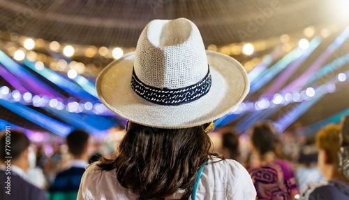 Back view of a young american woman fan of country music attending a country music concert wearing a cowboy hat and copy space