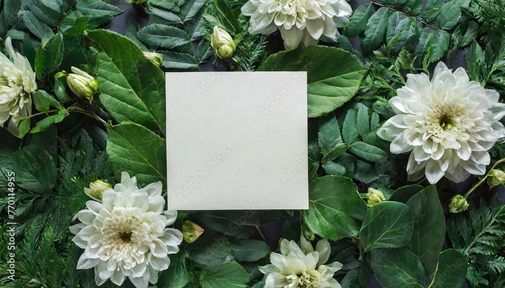 Creative layout made of flowers and leaves with paper card note. Flat lay. Nature concept 