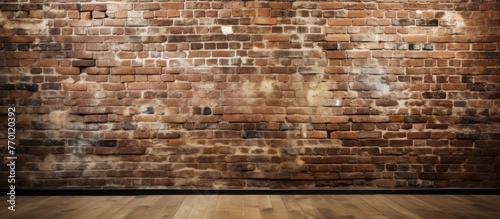 An empty room with a brown brick wall and wooden flooring. The brickwork is in a rectangular pattern, showcasing the beauty of natural building materials