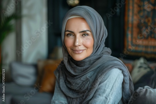 A woman wearing a grey scarf and a grey dress is smiling