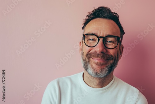 Portrait of a handsome middle-aged man with a beard and glasses on a pink background © Inigo