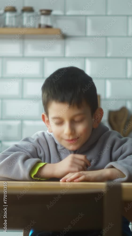 Vertical video. Sleepy boy sitting in the kitchen at home yawns and going to sleep on the table.	
