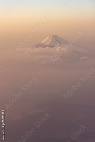 Mt. Fuji as seen from the air at dusk, bathed in a pink light, surround by clouds