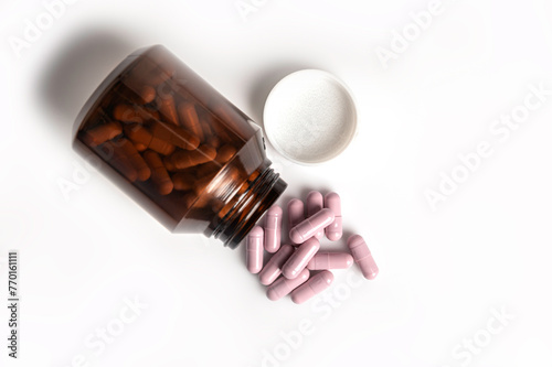 Top view of medicine pill spilling out of bottle on white background.