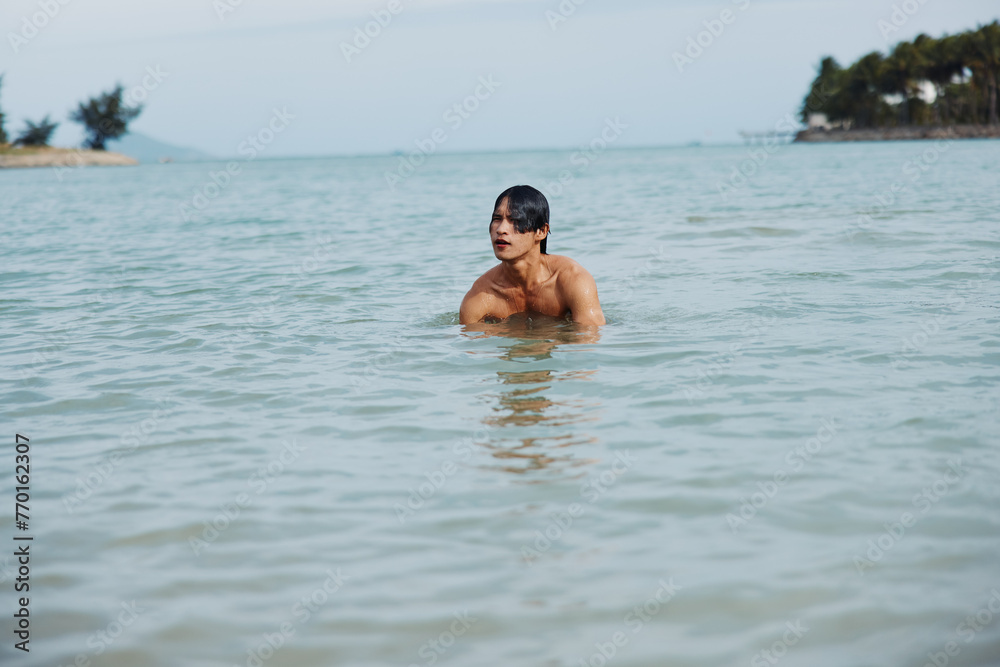 Active Asian Man Enjoying Fun Water Activities on a Tropical Beach Vacation