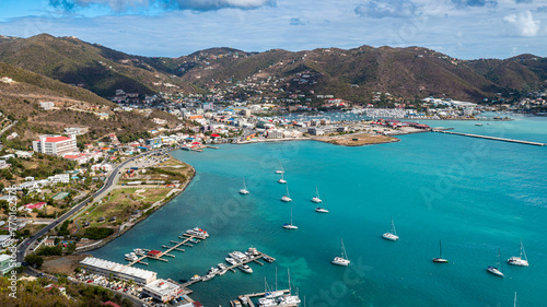 An aerial view showcases a vibrant harbor in the British Virgin Islands, where sailboats dot the turquoise sea