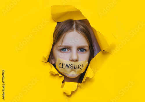 A child with his mouth taped shut peeks through a torn hole in yellow paper.The inscription on the tape is "CENSURE".Ban on opinion,unwillingness to listen to children,restriction of freedom of speech © shchus