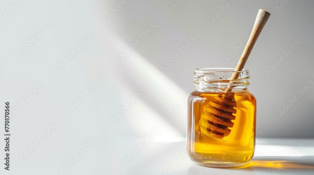 Glass jar full of honey and wooden stick on a white background. Glass jar full of honey and wooden stick on a white background.