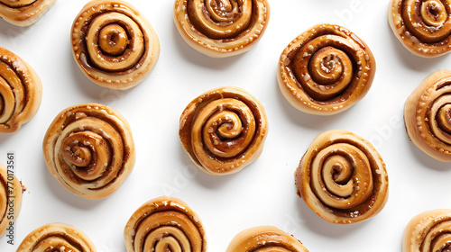 Cinnamon buns photographed from above, evenly distributed on a white background