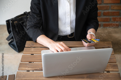 Cropped shot view of business woman holding credit card during using laptop for online shopping.