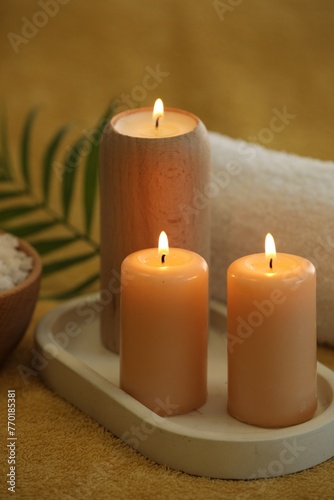 Spa composition with burning candles on soft yellow fabric