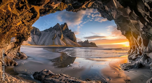 beautiful shot from inside an old brown cave viewing ocean and its waves coming to the beach on rocks and mountains during sunshine in the morning with the view of clouds and the sky