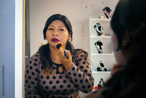 latina woman putting makeup powder on her face - beauty concept