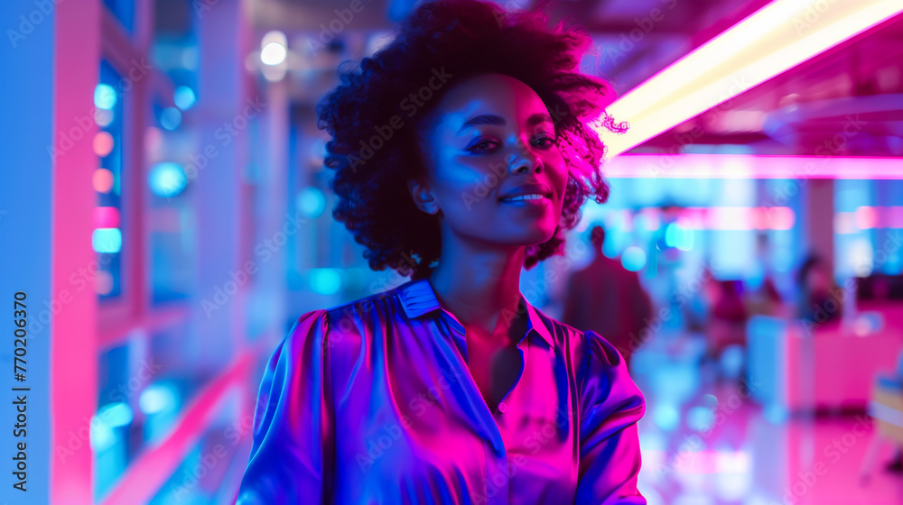 Happy woman in a purple blouse standing in a futuristic busy office with confidence, with bold blue, purple and pink colors. Happy woman in a purple blouse standing in a futuristic busy office with confidence, with bold blue, purple and pink colors.