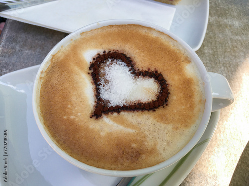 Cappuccino mit einem Kakao Herz auf verziertem Milchschaum photo