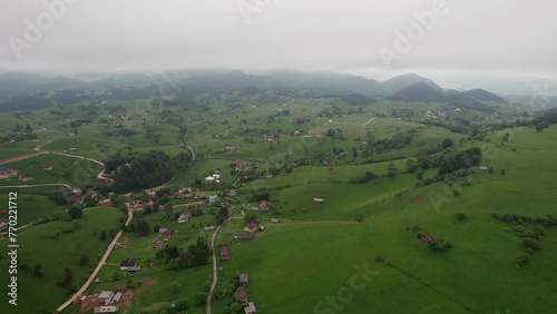 Misty morning over Sirnea Village with lush green hills and scattered houses, aerial view photo