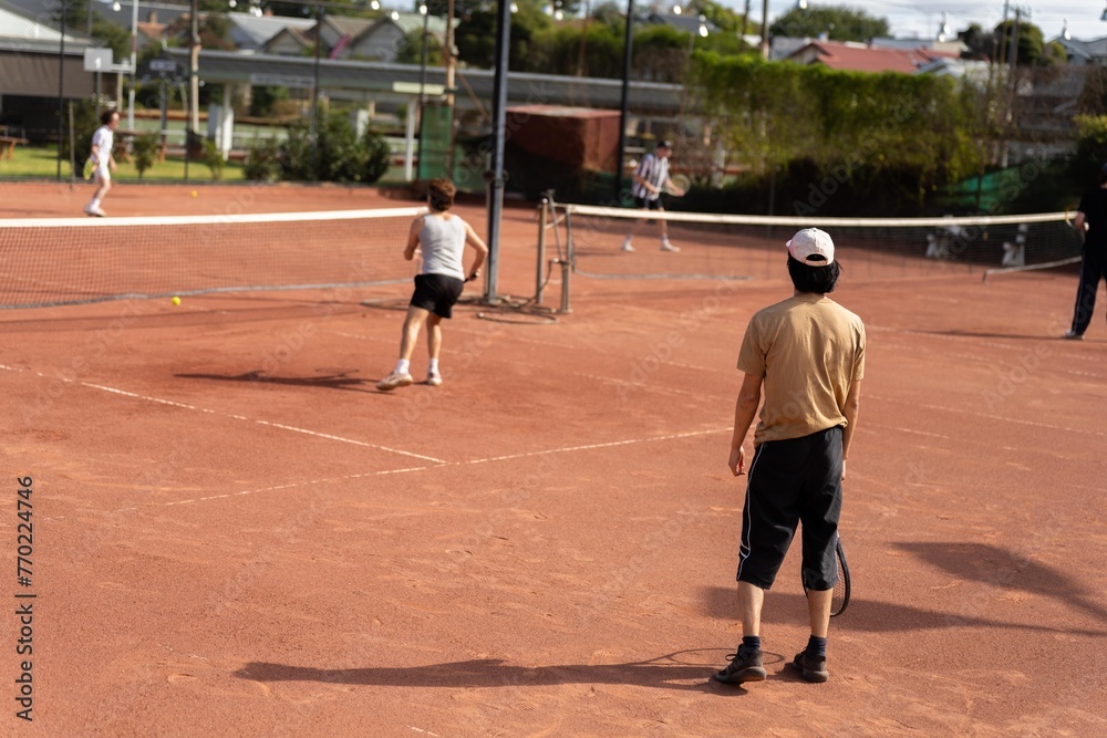 friends playing tennis on a clay court, watering and bagging a clay court. doing tennis court maintence