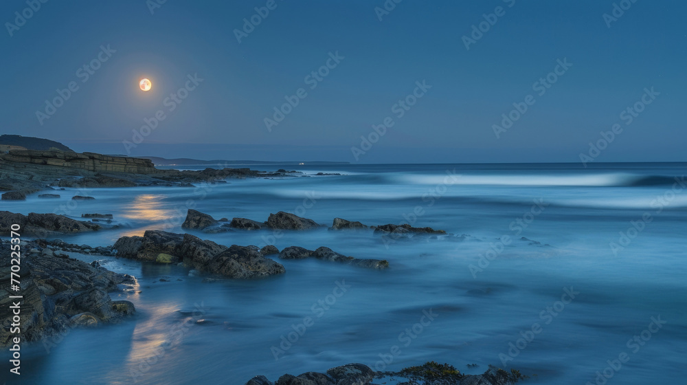 Small waves lap against a rocky shore mirroring the movements of the moon as it glides across the vast expanse of the night sky. . .