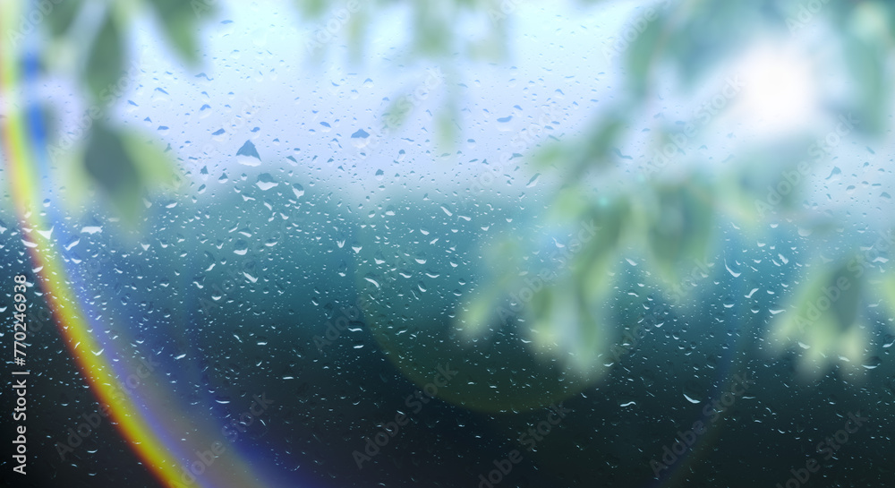 梅雨　雨の滴のついた窓ガラスと前面の木の葉とレンズフレア太陽の日差しの背景　ガラス越し奥の山林・森林の風景　6月・梅雨明け・水滴・日本・季節 - obrazy, fototapety, plakaty 
