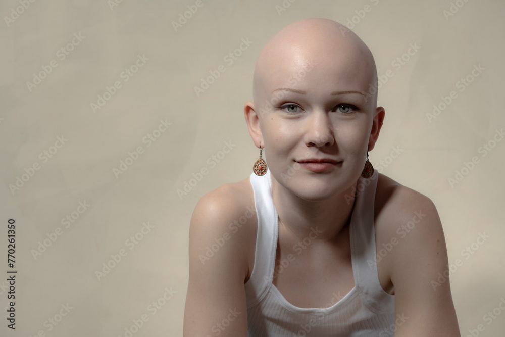 A calm and reflective bald woman sitting, hands on knees, against a light backdrop in a simple setting A calm and reflective bald woman sitting, hands on knees, against a light backdrop in a simple setting
