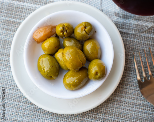 There is portion of pickled green olives in porcelain bowl.